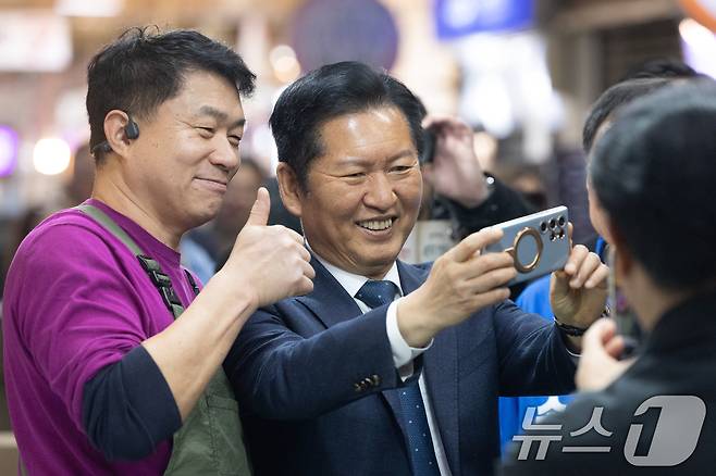 정청래 더불어민주당 대표가 12일 강원 속초관광수산시장을 찾아 상인과 셀카를 찍고 있다. 2026.4.12 ⓒ 뉴스1 이승배 기자