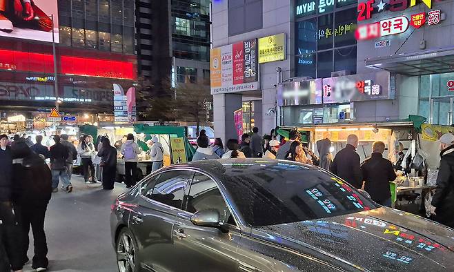 7일 오후 8시 서울 마포구 홍대입구역 9번 출구 앞 차도에 불법 노점상들이 줄지어 영업하는 가운데, 보행자와 차량이 지나가고 있다.