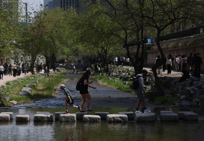 서울의 낮 최고기온이 25도까지 오르는 등 때 이른 초여름 날씨를 보인 13일 서울 청계천을 찾은 외국인들이 징검다리를 건너고 있다. 연합뉴스