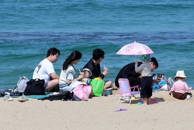 초여름의 날씨를 보인 13일 강원 강릉시의 한 해변에서 가족과 함께 나들이 온 아이가 장난감 양산을 쓰고 있다. 연합뉴스
