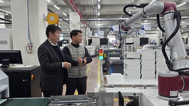 초중고교 교과서 제조업체 프린피아가 최근 물류 자동화와 협동 로봇 도입 등 스마트공장 전환에 성공했다. 서동일 프린피아 디지털센터 대표(왼쪽)와 김극 삼성전자 ESG&스마트공장지원센터 위원이 공장에 도입된 다관절 협동 로봇을 살펴보고 있다. 삼성전자
