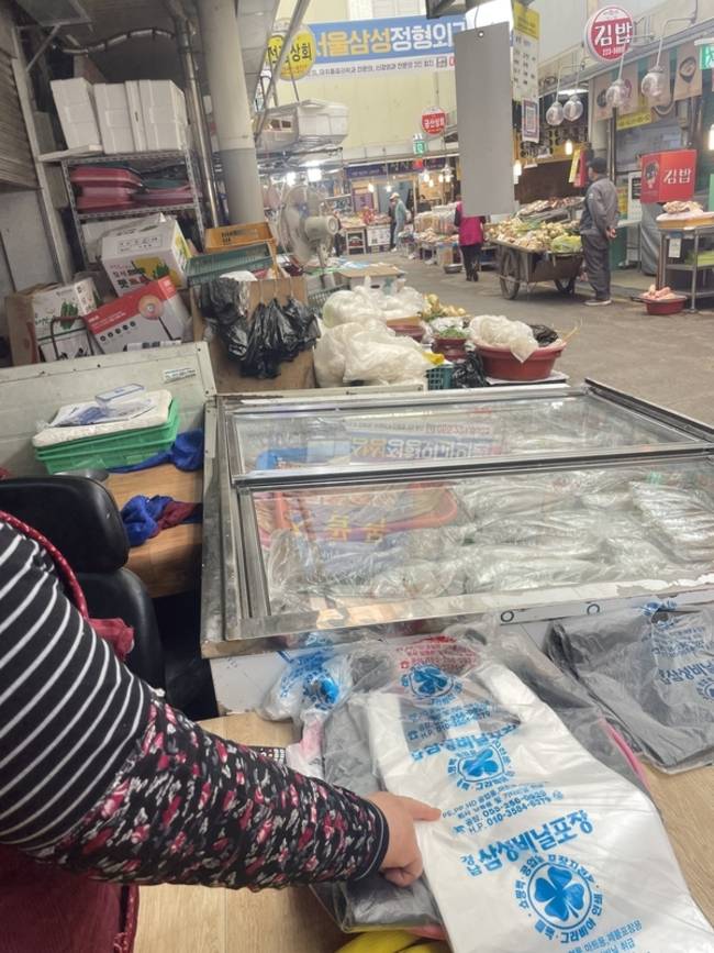 21일 마산 어시장에서 생선을 판매하는 상인이 하얀 봉투를 가리키며 가격이 올랐다고 설명하고 있다. /이미지 기자