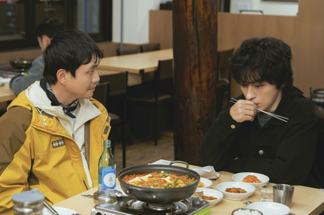 드라마 '모두가 자신의 무가치함과 싸우고 있다'에서 남의 불행에 행복해하는 동만과 그런 그와 똑같은 인간이고 싶지 않아 발버둥치는 경세가 김치찌개집에 마주 앉아 기싸움을 벌이는 장면. 스튜디오 피닉스·SLL·스튜디오 플로우 제공
