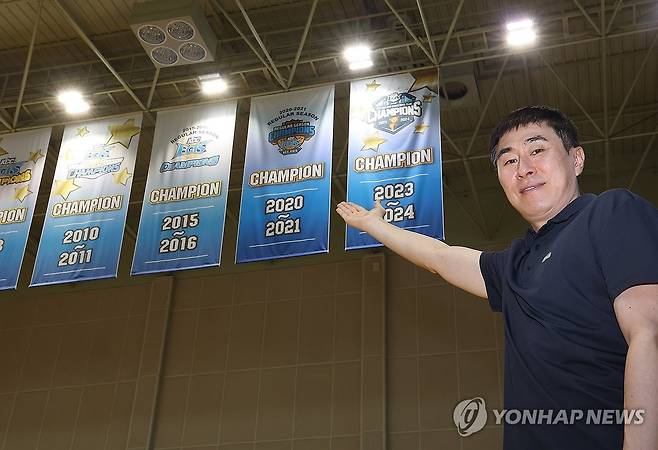 '여기가 새 우승 현수막 붙을 자리' (용인=연합뉴스) 김성민 기자 = 부산 KCC 이지스 이상민 감독이 15일 경기도 용인시 KCC 용인연습체육관에서 연합뉴스와 인터뷰하기 전 우승 현수막이 붙을 자리에 서서 기념 촬영을 하고 있다. 2026.5.16 ksm7976@yna.co.kr
