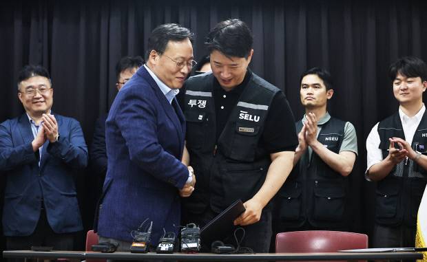 여명구(왼쪽) 삼성전자 DS(디바이스솔루션·반도체 사업 담당) 피플팀장과 최승호 삼성그룹 초기업노동조합 삼성전자지부 위원장이 20일 경기도 수원시 장안구 경기고용노동청에서 열린 삼성전자 임금협상 잠정 합의안에 서명한 후 손을 맞잡고 있다. /연합뉴스