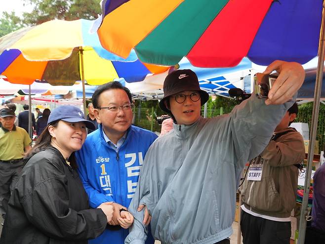 더불어민주당 김부겸 대구시장 후보가 21일 달성군 옥포·화원시장을 찾아 주민과 함께 손을 잡고 셀카를 찍고 있다. /김부겸 후보 캠프 제공