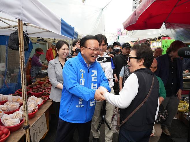 더불어민주당 김부겸 대구시장 후보가 21일 달성군 옥포·화원시장을 찾아 한 주민과 반갑게 웃으며 악수하고 있다. /김부겸 후보 캠프 제공