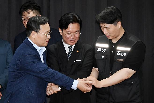 20일 경기도 수원시 장안구 경기고용노동청에서 열린 삼성전자 임금협상을 마친 후 여명구 삼성전자 DS(디바이스솔루션·반도체 사업 담당) 피플팀장과 최승호 삼성그룹 초기업노동조합 삼성전자지부 위원장이 잠정 합의안에 서명한 후 김영훈 고용노동부 장관과 손을 잡고 있다./연합뉴스