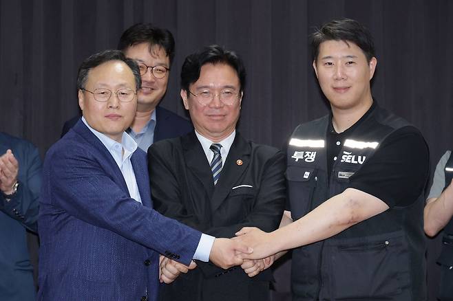 20일 경기도 수원시 장안구 경기고용노동청에서 열린 삼성전자 임금협상을 마친 후 여명구 삼성전자 DS(디바이스솔루션 반도체 사업 담당) 피플팀장과 김영훈 고용노동부 장관, 최승호 삼성그룹 초기업노동조합 삼성전자지부 위원장이 잠정 합의한에 서명한 후 손을 맞잡고 있다. 김성룡 기자 / 2026.05.20