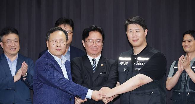 20일 경기도 수원시 장안구 경기고용노동청에서 열린 삼성전자 임금협상을 마친 후 여명구 삼성전자 DS(디바이스솔루션·반도체 사업 담당) 피플팀장과 최승호 삼성그룹 초기업노동조합 삼성전자지부 위원장이 잠정 합의안에 서명한 후 김영훈 고용노동부 장관과 손을 맞잡고 있다. 연합뉴스