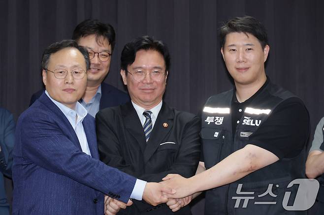 20일 경기도 수원시 장안구 경기고용노동청에서 열린 삼성전자 임금협상을 마친 후 여명구 삼성전자 DS(디바이스솔루션·반도체 사업 담당) 피플팀장과 김영훈 고용노동부 장관, 최승호 삼성그룹 초기업노동조합 삼성전자지부 위원장이 잠정 합의한에 서명한 후 손을 맞잡고 있다. (공동취재) 2026.5.20 ⓒ 뉴스1 김영운 기자