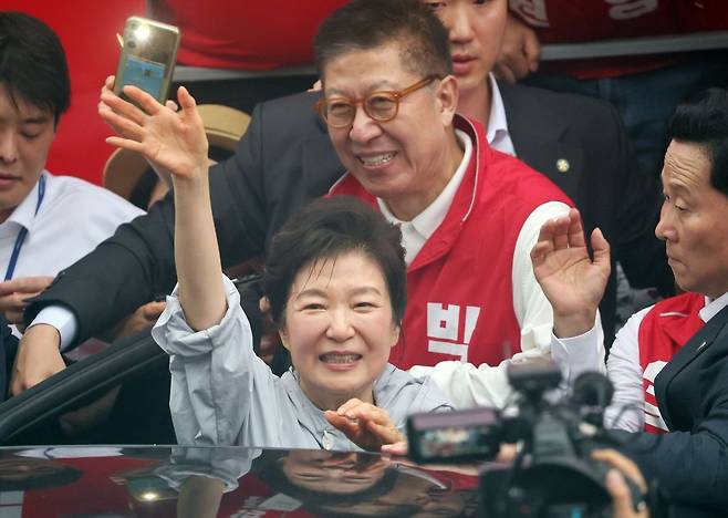 박근혜 전 대통령이 지난 27일 부산 기장군 기장시장을 찾아 국민의힘 박형준 부산시장 후보와 박민식 북갑 보궐선거 후보와 함께 시민들과 인사한 뒤 차량에 탑승하며 손을 흔들고 있다. 연합뉴스