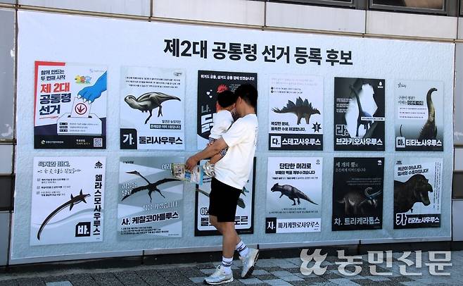 제2대 공통령 선거의 후보 전단지를 살펴보는 부자.