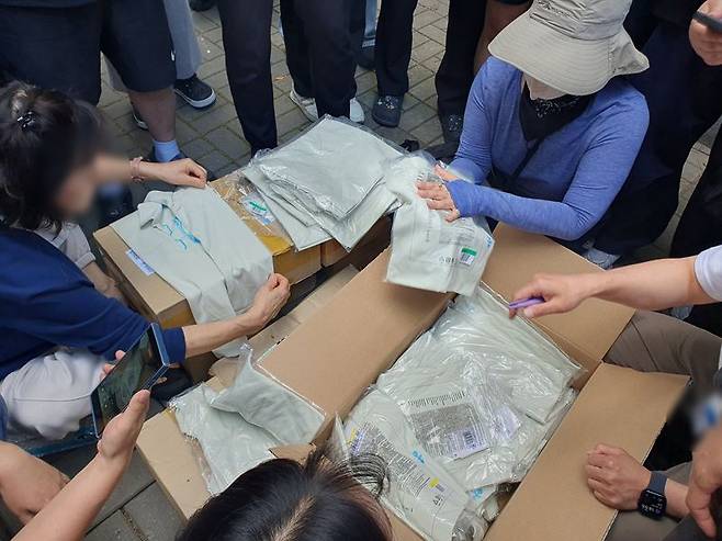 6·3 지방선거 투표용지 부족 사태로 개표가 진행 중인 서울 송파구 올림픽공원 핸드볼경기장 인근에서 5일 오후 시위대들이 택배상자를 열어 내용물을 확인하고 있다. 해당 상자에서는 대회용 티셔츠 등이 확인됐다. 사진=최승한 기자