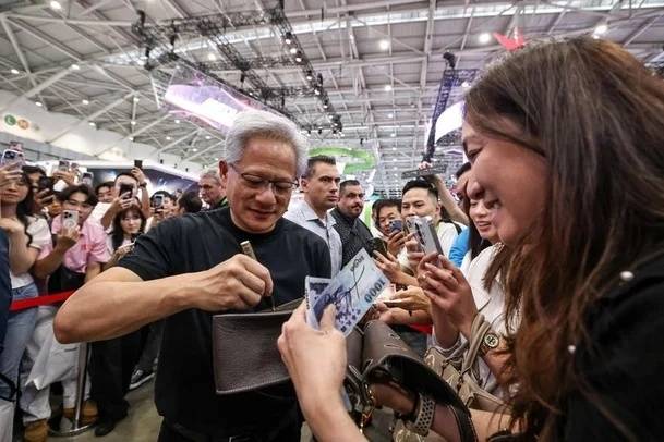 젠슨 황 엔비디아 최고경영자(CEO)가 지폐와 지갑에 사인을 하고 있다. AFP 연합뉴스