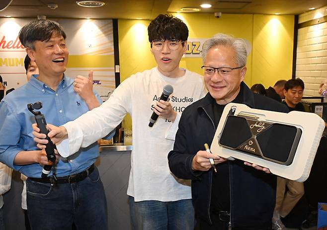 젠슨 황 엔비디아 최고경영자(CEO)가 7일 서울 강남구 옵티멈존 PC카페에서 크래프톤 유저에게 선물할 최신 그래픽카드 ‘지포스RTX5090’에 사인하고 있다. 왼쪽 첫째는 장병규 크래프톤 의장. (공동취재)