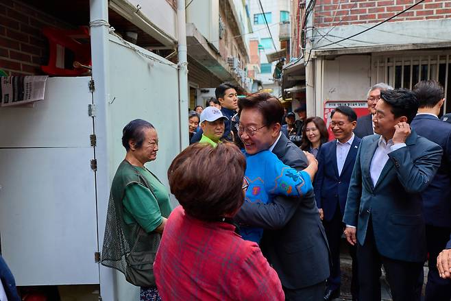 이재명 대통령이 지난달 21일 서울 종로구 돈의동 쪽방촌을 방문해 주민들과 인사를 나누던 모습 <연합>