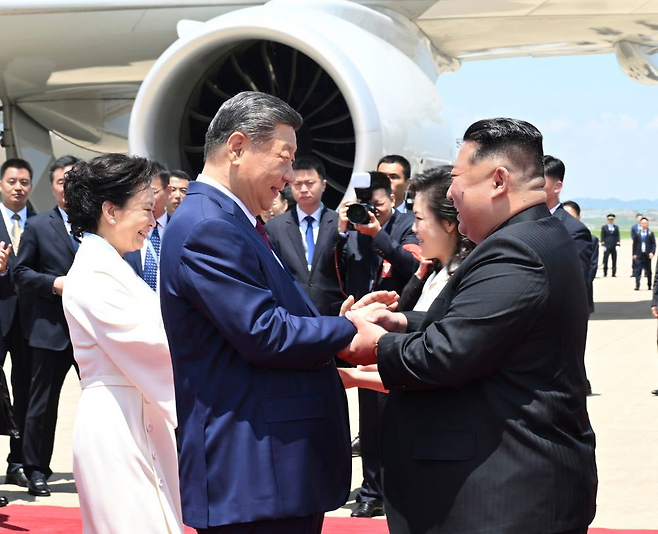 8일 북한 평양 순안공항에 도착한 시진핑 중국 국가주석(앞줄 왼쪽)과 김정은 북한 국무위원장(앞줄 오른쪽)이 환하게 웃으며 손을 맞잡고 있다. 시 주석의 부인 펑리위안 여사(뒷줄 왼쪽)와 김 위원장의 부인 리설주(뒷줄 오른쪽) 또한 남편들의 곁에서 인사하고 있다. 평양=신화망