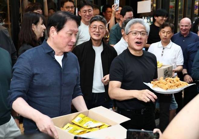 젠슨 황 엔비디아 최고경영자(CEO)와 최태원 SK 회장이 지난 7일 서울 강남구 깐부치킨 삼성점에서 치맥 회동을 하던 중 HBM 칩과 치킨을 나눠주고 있다. 연합뉴스