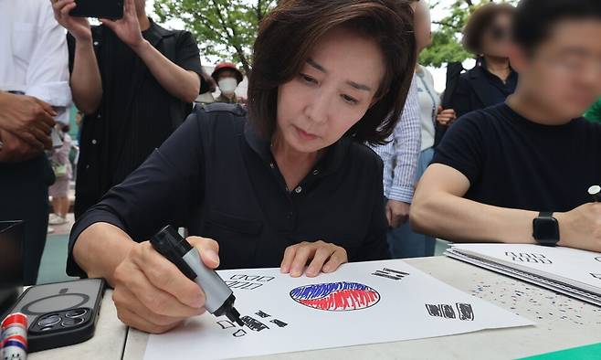 6·3 지방선거 투표용지 부족 사태로 촉발된 잠실 ‘개표소 봉쇄 시위’가 열흘째 이어지고 있는 14일 오후 서울 송파구 올림픽공원 핸드볼경기장 인근에서 나경원 국민의힘 의원이 태극기를 그리고 있다. 최현수 기자 emd@hani.co.kr
