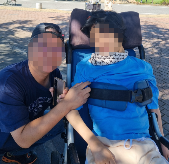 뇌병변 및 지적 장애(중복장애)가 있는 조모씨(오른쪽)와 아버지. 조씨 부모님은 조씨를 데리고 장애인 콜택시 등을 이용해 차로 30분 거리 병원에서 재활치료를 하고 있다. /조씨 어머니 제공