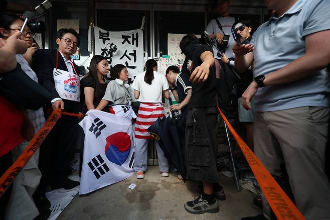 6.3지방 선거에서 투표용지가 부족한 사태에 대해 부정선거라고 주장하는 시민들이 서울 송파구 개표소인 올림픽공원 내 핸드볼경기장 출입을 봉쇄한 가운데 16일 오후 14시 50분 시민 한 명이 문을 가로 막아 체육회 인원들과 국민의힘 의원들이 건물 안으로 들어가지 못하고 있다. 장동혁 국민의힘 대표는 한 사람이라도 반대하면 들어가지 않겠다고 밝히고 있다. 조태형 기자