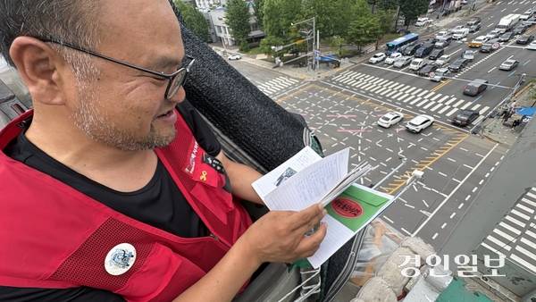 6일 오후 택시기사 최저임금 보장을 위한 근로기준법 시행령 개정을 촉구하며 인천 남동구 통신탑에 올라 고공농성에 나선 택시기사 고영기씨가 동료 노조원과 시민사회단체 활동가들이 보낸 편지를 읽고 있다. 2026.7.6 /정선아기자 sun@kyeongin.com