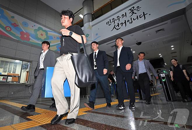 6·3 지방선거 투표용지 부족 사태를 수사하는 검경 합동수사본부 수사관들이 11일 경기도 과천시 중앙선거관리위원회에 대한 압수수색을 마친 뒤 압수품을 들고 건물을 나오고 있다. (공동취재) 2026.6.11 ⓒ 뉴스1 이호윤 기자
