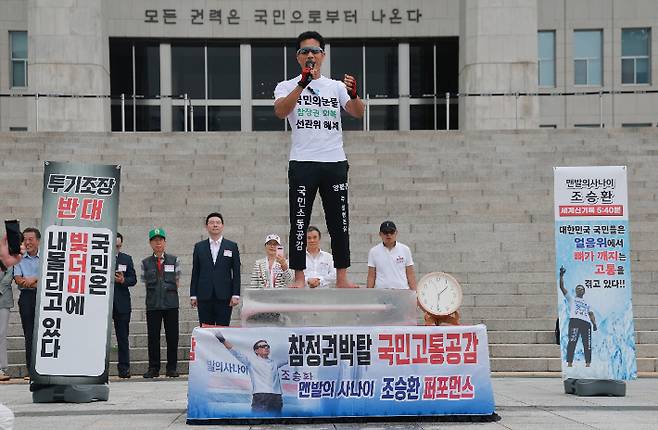 23일 국회 본청 앞 계단에서 국민의힘 최수진 의원이 보완수사권 폐지 반대, 선거관리위원회 해체 등을 촉구하기 위해 연 '국민은 고통 받고 있다' 행사에서 환경운동가 조승환 씨가 맨발로 얼음 위에 서 있는 퍼포먼스를 하고 있다. 연합뉴스