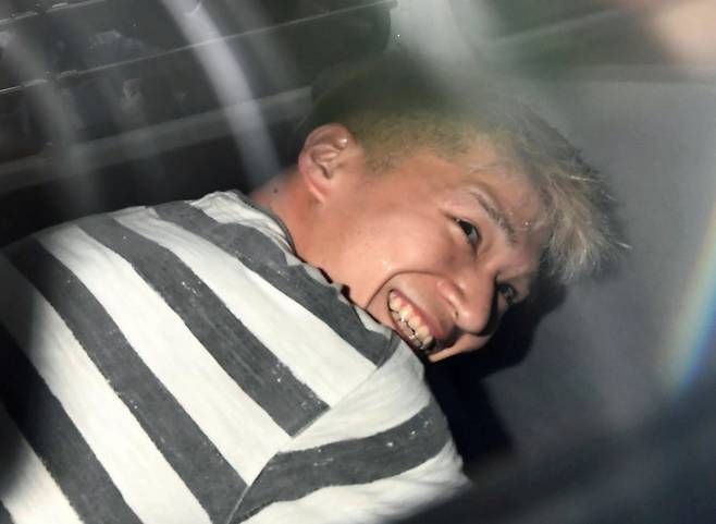 일본 도쿄의 사가미하라 장애인 시설 흉기 난동 사건의 범인 우에마쓰 사토시(植松聖·당시 26세)가 2016년 7월 27일 요코하마지방검찰청으로 송치되던 중 취재진들 앞에서 섬뜩한 미소를 보였다. /로이터=뉴스1