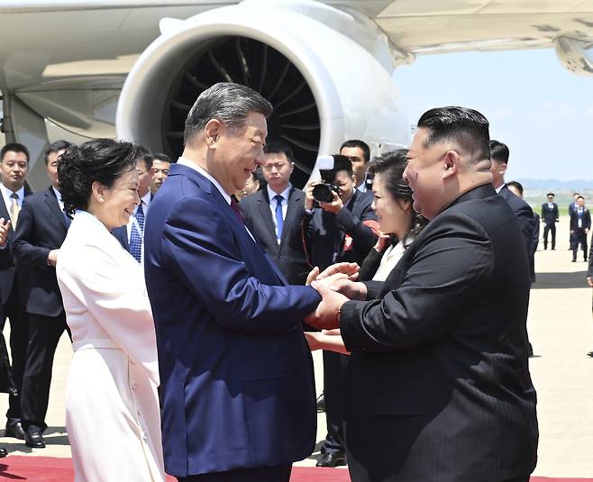 김정은(오른쪽) 북한 국무위원장이 8일 평양 순안공항에 도착한 시진핑 중국 국가주석과 손을 맞잡으며 환하게 웃고 있다. 김 위원장의 부인 리설주 여사도 시 주석과 동행한 펑리위안 여사를 영접했다. 신화연합뉴스