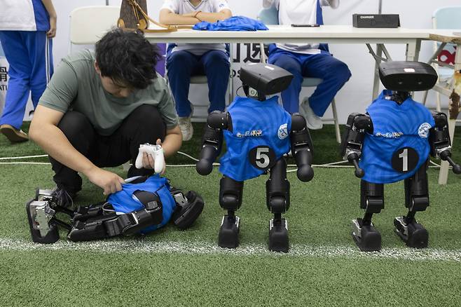 14일 중국 베이징에서 열린 2026 세계 휴머노이드 로봇 운동회 미디어 사전 공개 행사에서 한 팀원이 축구 경기 휴식 시간에 휴머노이드 로봇을 점검하고 있다. 올해로 2회째를 맞은 이 대회는 8월 22일부터 26일까지 개최될 예정이다. 베이징/EPA연합뉴스