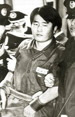 1974년 10월 7일, 대통령 저격 미수 사건의 범인 문세광이 첫 재판이 열린 서울형사지법 대법정에 들어서고 있다. 자해를 막기 위해 안경을 벗겼고 가죽 수갑을 채웠다. /조선일보 DB