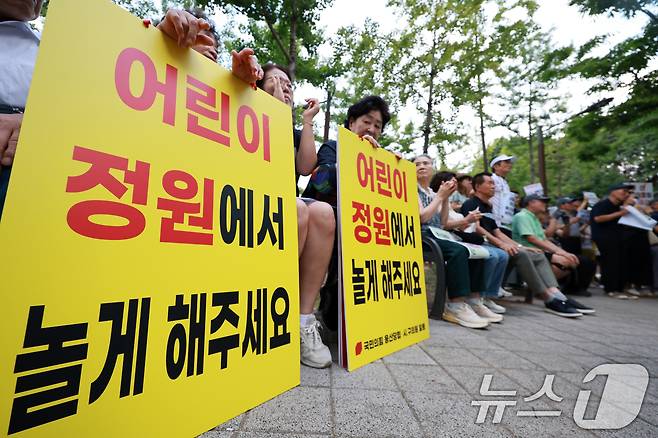 용산 주민들이 19일 서울 용산구 한마음공원에서 열린 '용산어린이정원 사수 궐기대회‘에서 피켓을 들며 용산어린이정원 일대 주택 공급 개발을 반대하고 있다. 2026.8.19 ⓒ 뉴스1 이호윤 기자