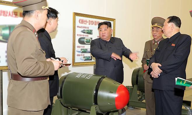 김정은 북한 국무위원장이 전술핵무기 화산-31 앞에서 관계자들과 대화를 하고 있다. 노동신문·뉴스1