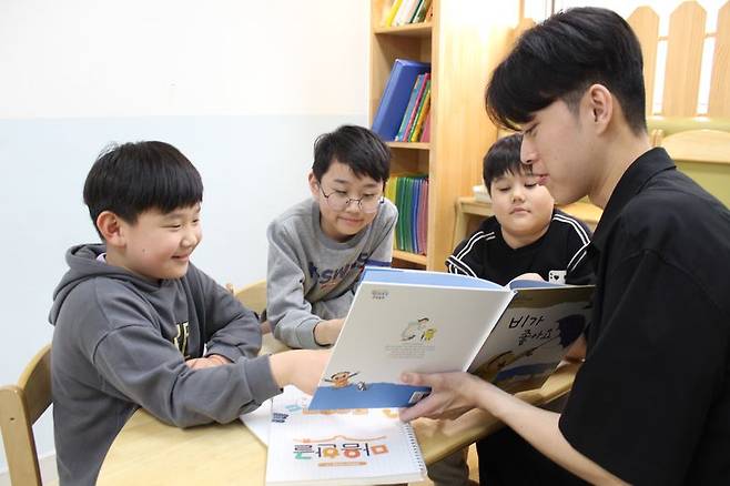 현대해상이 다문화 아동의 학습능력 향상과 정서발달을 위해 운영하는 '마음한글'의 대학생 멘토가 다문화 아동들에게 동화책 한글 수업을 진행하고 있다.