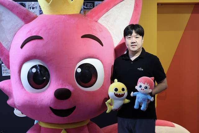 김민석 더핑크퐁컴퍼니 대표가 최근 서울 서초구 사옥에서 포즈를 취했다. 왼쪽 큰 조형물은 핑크퐁, 김 대표가 들고 있는 인형은 아기상어(왼쪽), 베베핀(오른쪽).