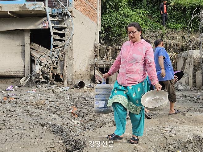 지난 1일(현지시간) 네팔 누와코트의 한 마을에서 주민이 토사 속에 파묻혀 있던 물건들을 옮기고 있다. 박민규 기자