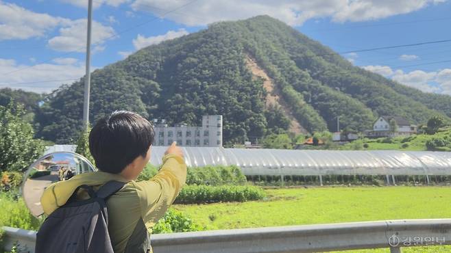 ◇4일 산사태 발생 당시 119에 최초 신고한 박정빈(23)씨가 사고 지점을 손으로 가리키고 있다. 사진=고은기자