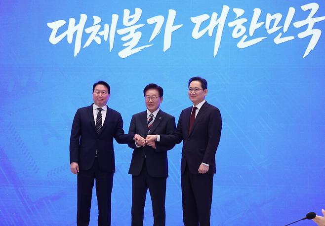 이재명 대통령(가운데)과 이재용 삼성전자 회장(사진 오른쪽), 최태원 에스케이(SK)그룹 회장이 지난 6월29일 청와대에서 열린 ‘대한민국 대도약 3대 메가프로젝트 국민보고회’에서 손을 맞잡고 있다. 청와대사진기자단