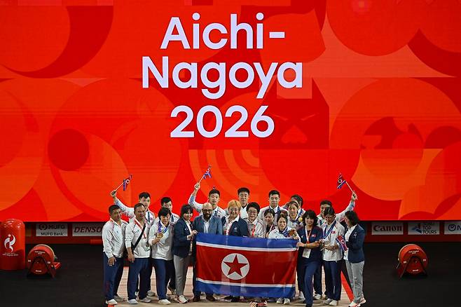 북한 역도 선수단이 28일 일본 나고야시 중소기업진흥회관에서 열린 2026 아이치·나고야 아시안게임 역도 남자 85㎏급 시상식이 끝난 뒤 금메달을 목에 건 로광렬(가운데)과 함께 시상대에서 기념사진을 찍고 있다. 북한 역도는 이번 대회에 출전한 10명 전원이 메달을 따 금 7개, 은 2개, 동 1개를 기록했다. 나고야=하상윤 기자