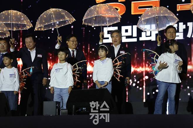 오늘(14일) 경남도민의 날 기념식에서 (오른쪽부터) 박완수 경남도지사, 박준 경남도의회 의장, 권순기 경남도교육감, 강기윤 창원시장이 어린이들에게 받은 '별빛 우산'을 펼쳐 들고 있다. 사진=정수연 기자