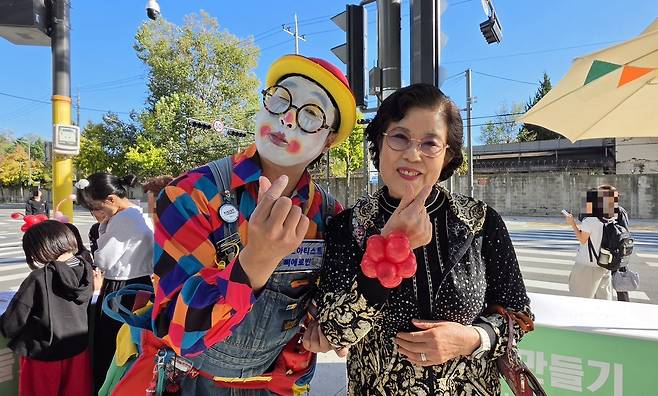 서울 용산구 주민 장순옥(77)씨와 신씨가 손가락 하트를 그리며 사진을 찍고 있다. 장씨 손목엔 신씨가 만들어 준 빨간 풍선 꽃팔찌가 채워져 있다. 백재연 기자