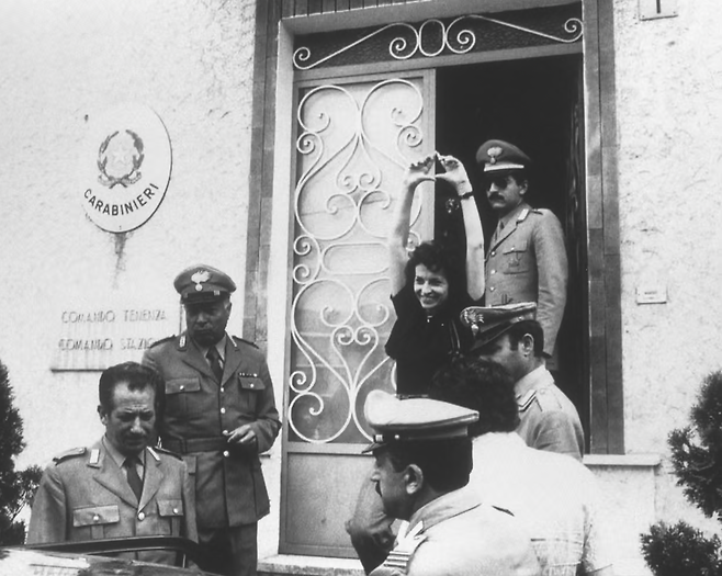 1975년 고향 브라의 카라비니에리(Carabinieri) 경찰서 앞에서 페미니즘의 손가락 상징을 그려 보이며 환하게 웃는 엠마 보니노. 지방선거 다음 날 다수의 이탈리아 주요 매체들은 투표 관련 사진 대신 저 사진을 1면 톱 사진으로 보도했다. 게티 이미지