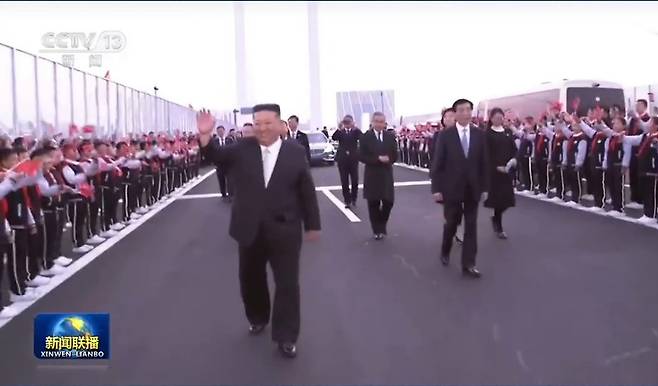 김정은 북한 노동당 총비서가 24일 중국 랴오닝성 단둥을 방문한 가운데, 신압록강대교에서 환영 인파를 향해 손을 흔들며 이동하고 있다. 김 총비서의 단둥 방문에는 왕후닝 중국공산당 중앙정치국 상무위원 겸 전국인민정치협상회의(정협) 주석이 동행했다. (중국 CCTV 화면 캡처)