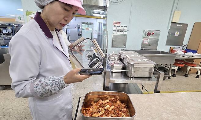 지난 27일 오후 2시께 경기 용인시 기흥구 성지고등학교 급식실에서 오기옥 영양교사가 전용 용기에 담긴 학교급식 예비식을 촬영해 예비식 유통 전 과정을 관리하는 디지털 플랫폼에 올리고 있다.